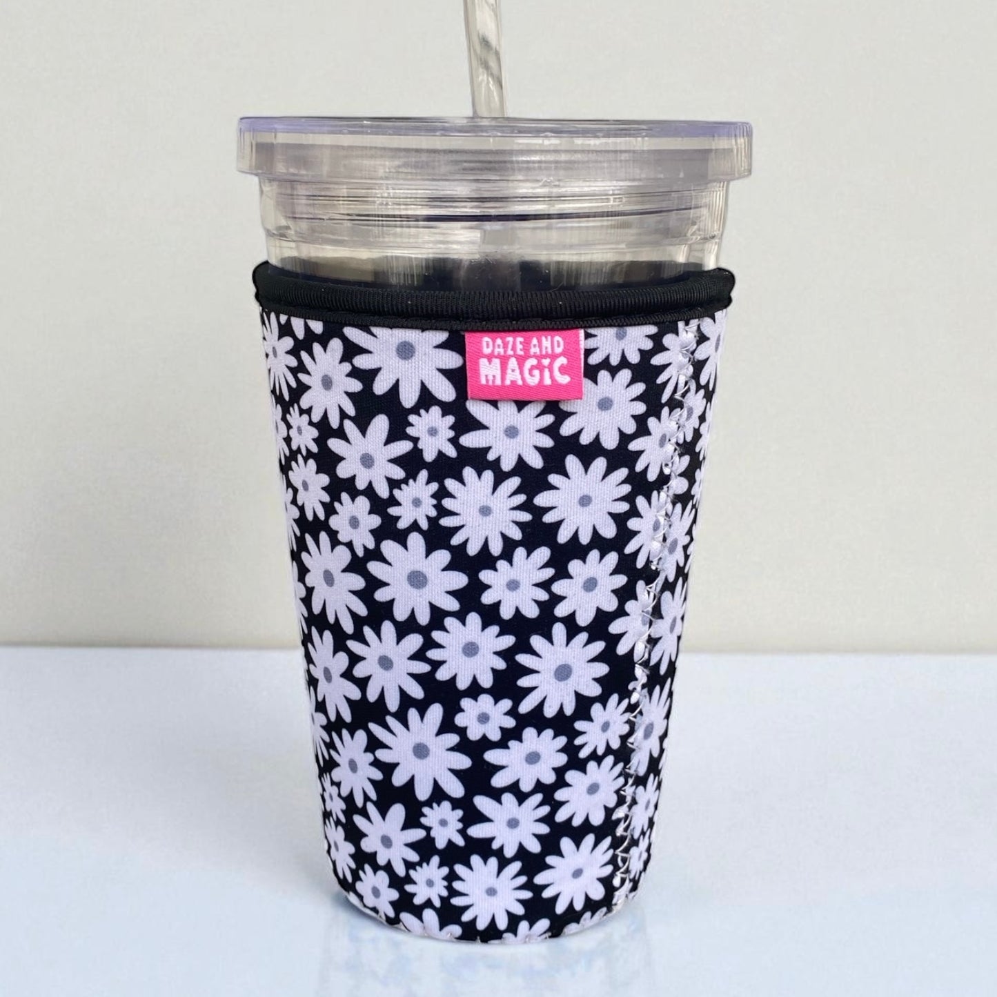 Close-up of Daisy Daze iced coffee sleeve showing daisy floral pattern and neoprene texture