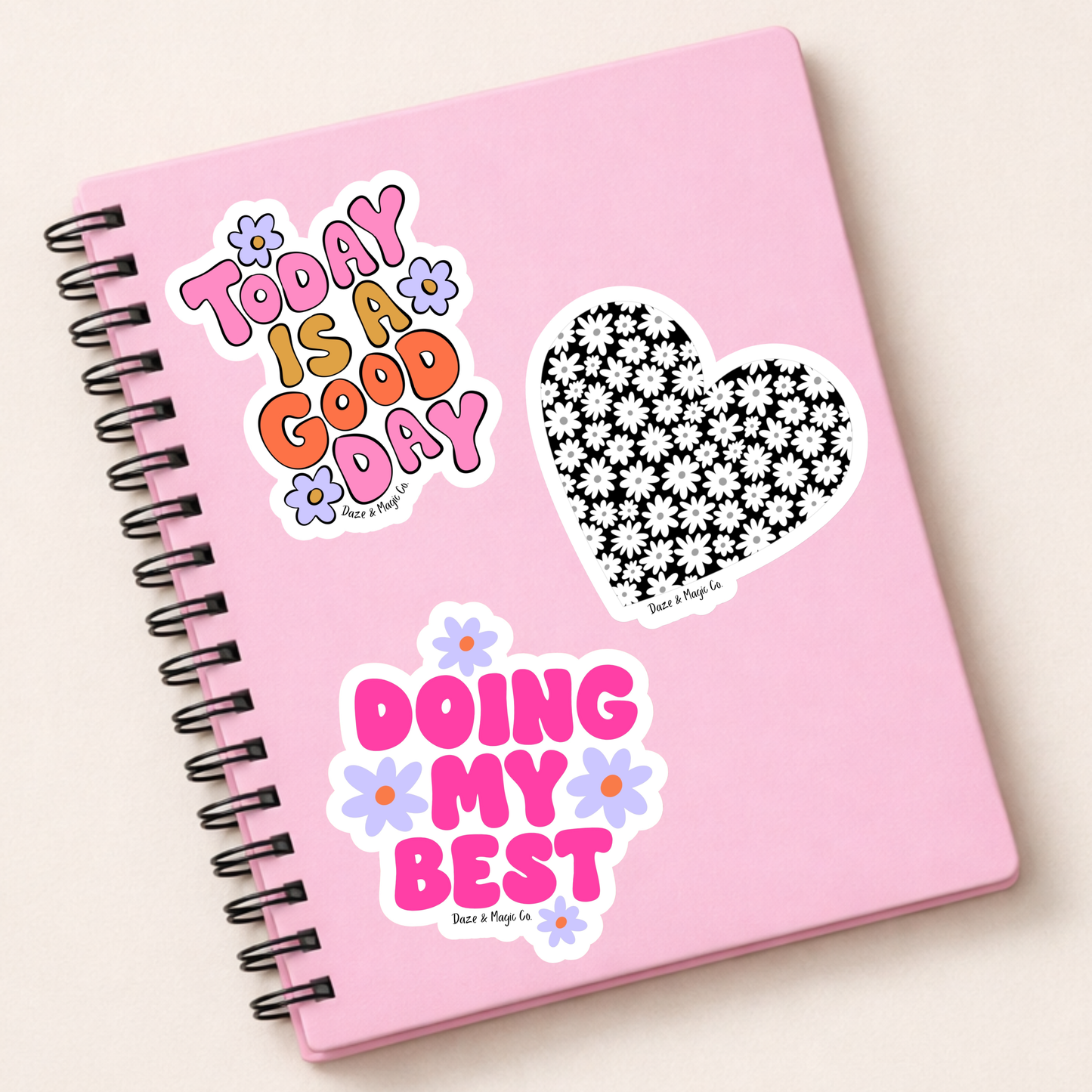 Pink notebook with motivational stickers on a light beige background