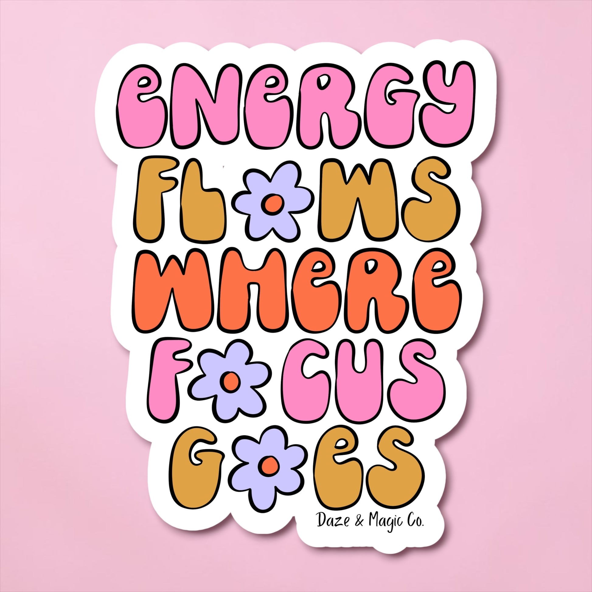 Colorful sticker with motivational quote 'Energy flows where focus goes' on a pink background