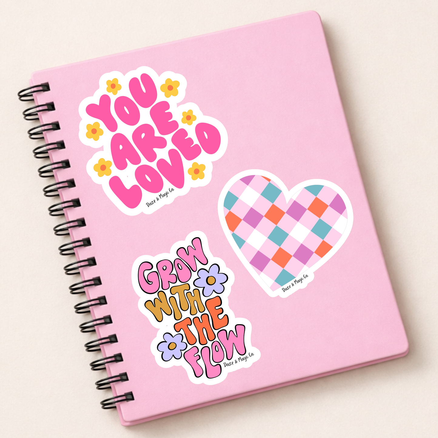 Pink notebook with decorative stickers on a light beige background