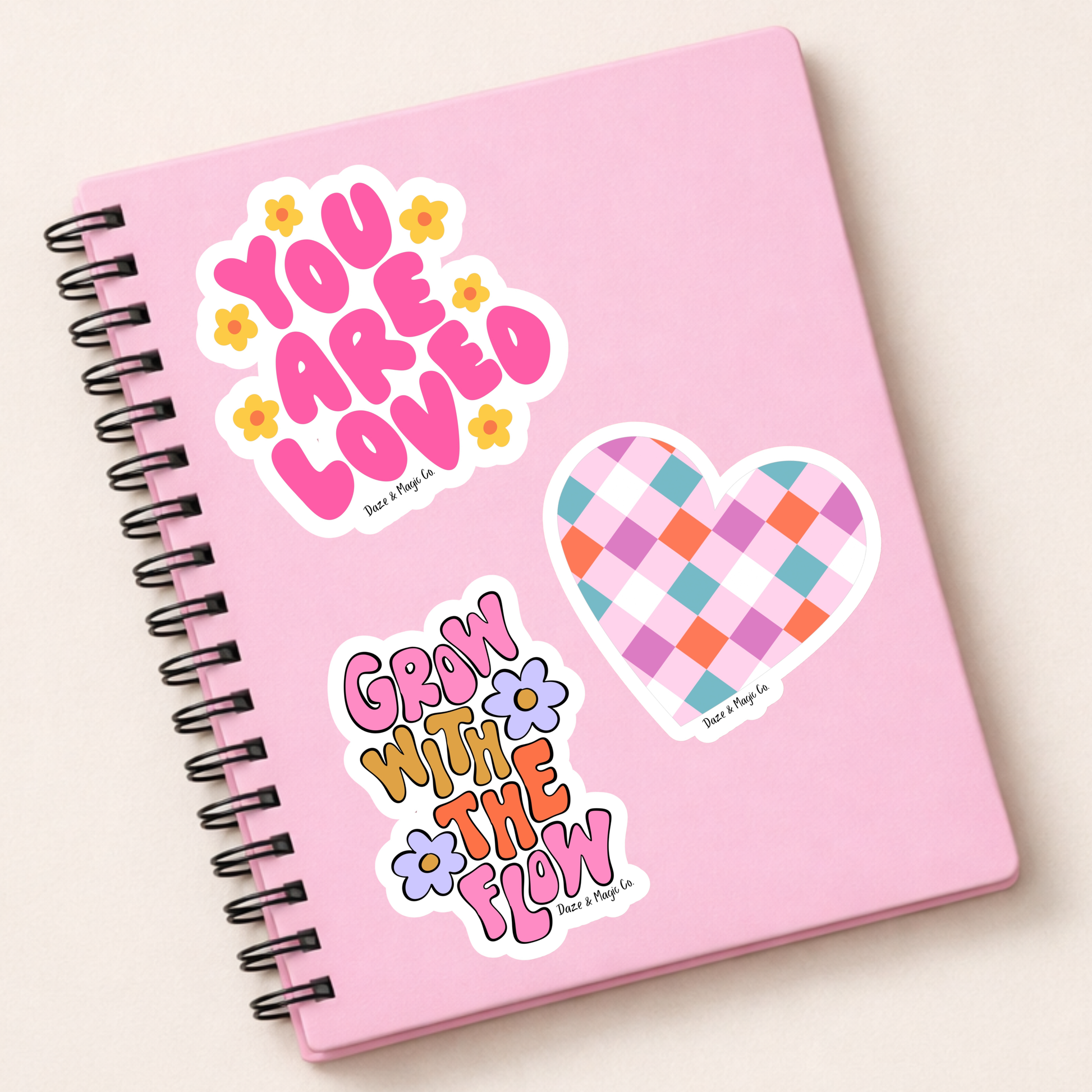 Pink notebook with decorative stickers on a light beige background