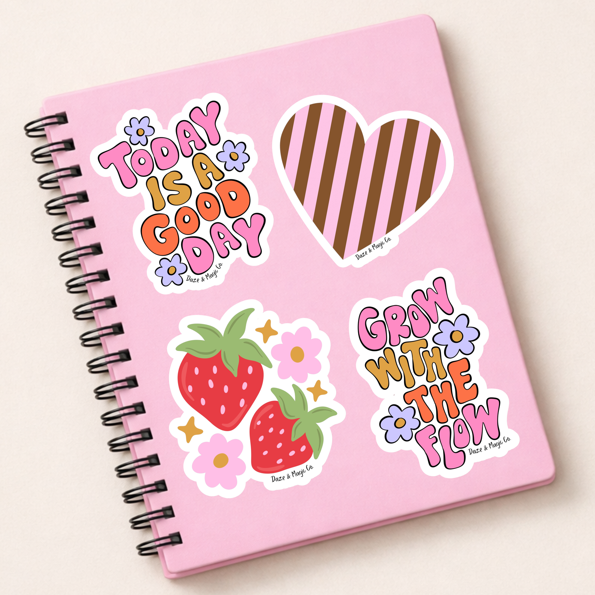 Pink notebook with colorful stickers on a light beige background