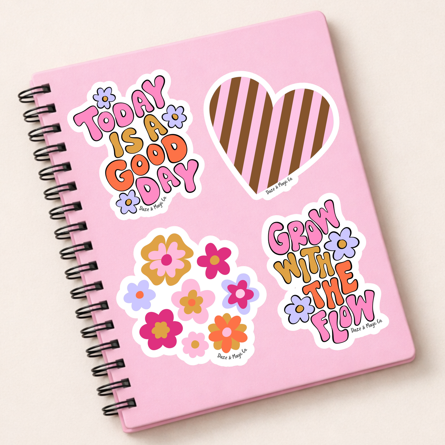 Pink notebook with colorful stickers on a light beige background