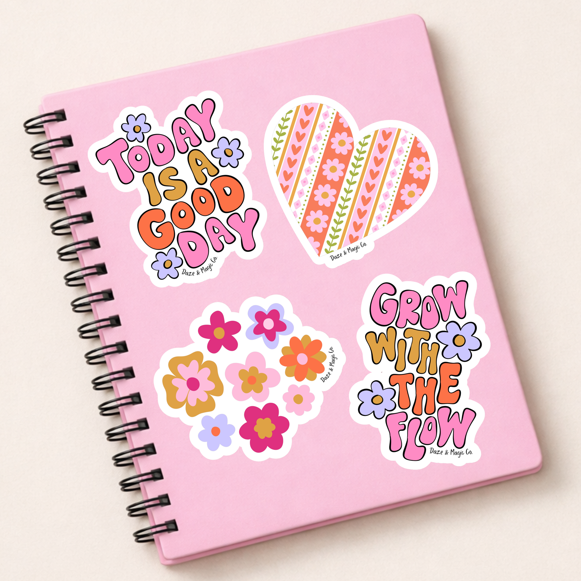 Pink notebook with colorful stickers on a light beige background