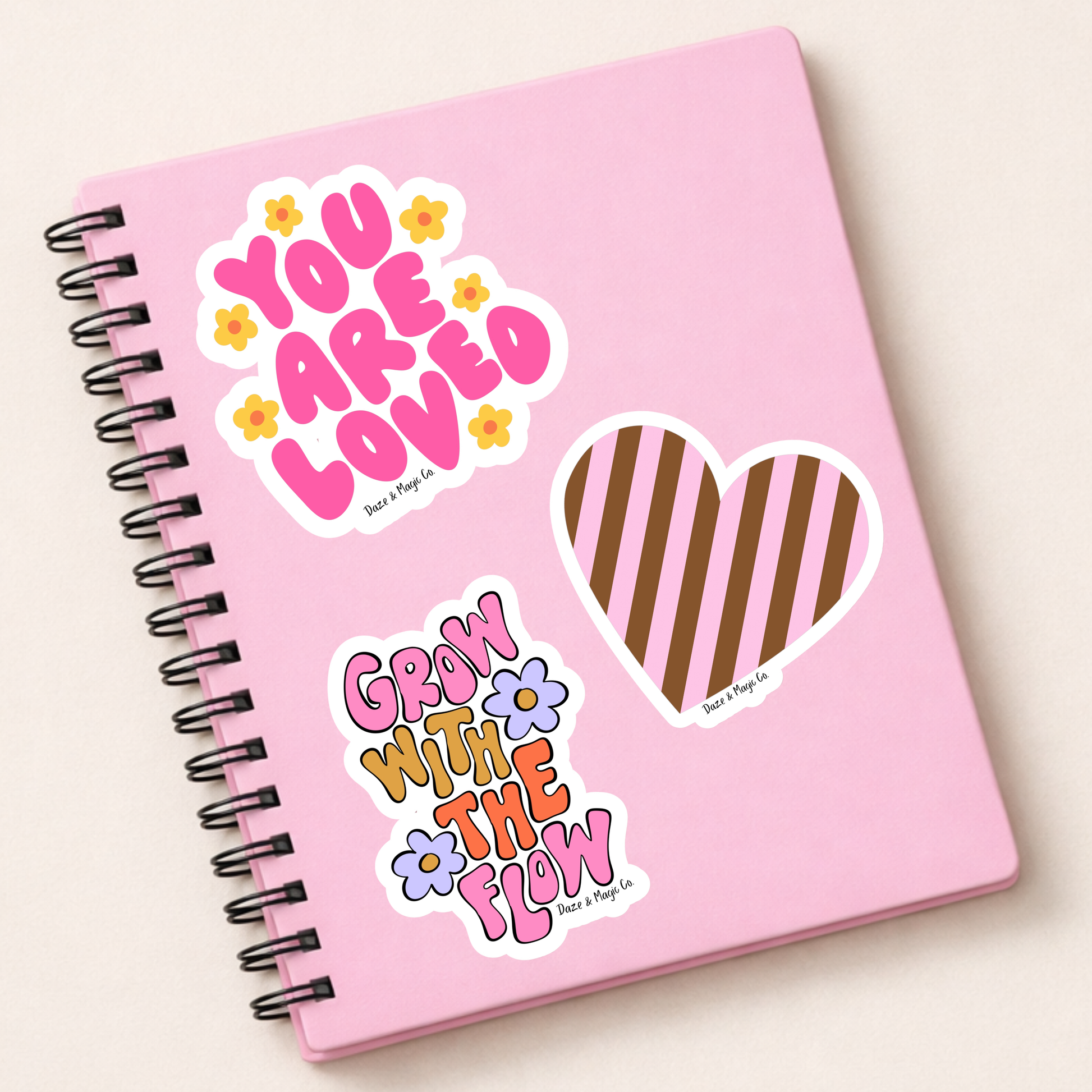 Pink notebook with decorative stickers on a light beige background